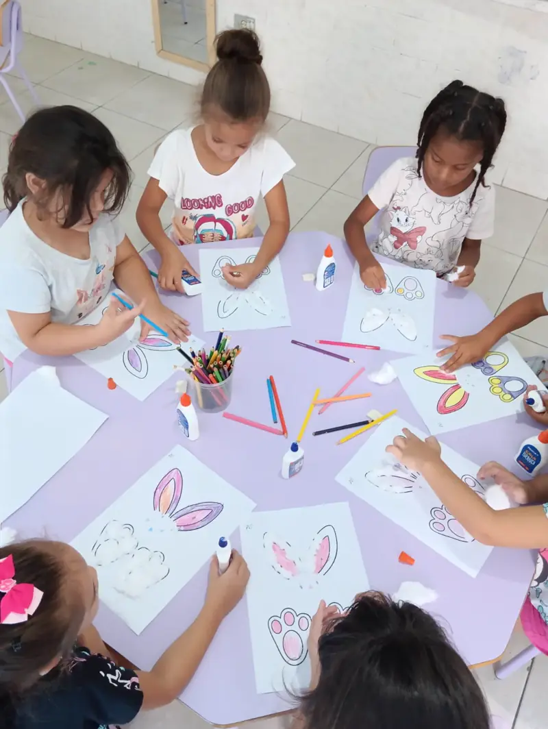 Crianças pequenas desenhando e colorindo juntas numa mesa
